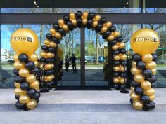 black and gold balloons in front of an entrance to a building with the words studio on it