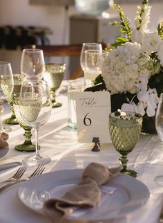 the table is set with white flowers and wine glasses