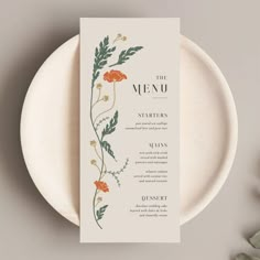 the menu card is sitting on top of a white plate with orange flowers and green leaves