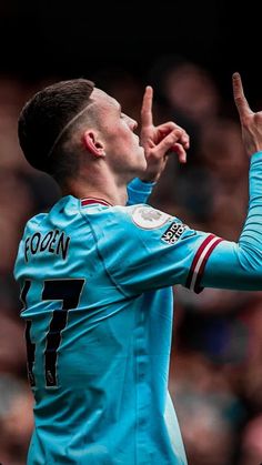 a soccer player is making the peace sign with his hand while standing in front of an audience