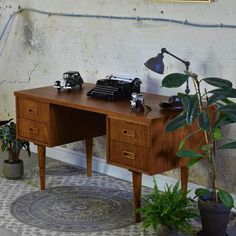 an old fashioned desk with a telephone on it and some potted plants next to it