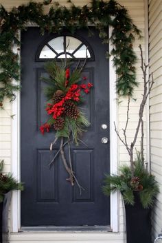 a black front door decorated for christmas with evergreen and poinsettis on it