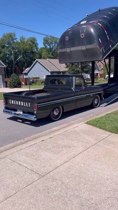 an old pickup truck parked in front of a house with a plane on it's roof