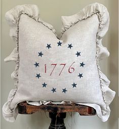 a white pillow with red and blue stars on it sitting on top of a wooden stand