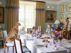 children sitting at a table with giraffes on the wall