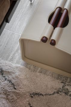 an upholstered white leather bench with two wooden handles