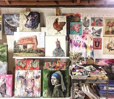 many paintings and pictures are hanging on the wall in this art studio with easel