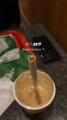 a cup with a straw in it sitting on a counter next to a cell phone