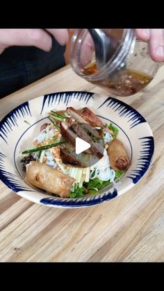 a person is pouring something into a plate with food on the table next to them