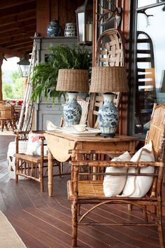 an outdoor area with wicker furniture and blue and white vases on the table