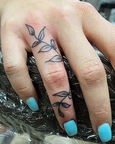 a woman's hand with a flower tattoo on her left thumb and ring finger