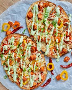 two pizzas sitting on top of a white plate covered in sauce and veggies