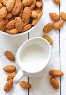 almonds and milk in bowls on white wooden table