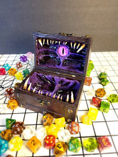 an open box filled with colorful dice on top of a white tiled floor next to other dice