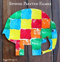 an elephant made out of colored paper sitting on top of a wooden table with the words sponge painted