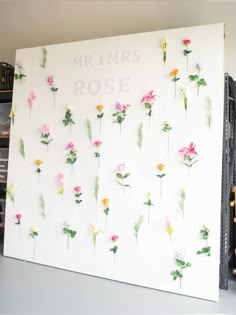 a white wall with flowers on it and the words mr & mrs rose written in pink