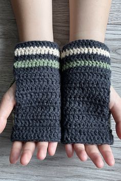 two hands wearing knitted wrist warmers on top of a wooden table