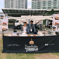 a man and woman standing behind a table with food on it