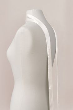 a white mannequin with a ribbon around it's neck