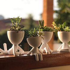 three ceramic planters sitting on top of a window sill with succulents in them