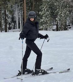 a woman on skis in the snow with trees in the backgrouund