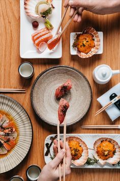 people are eating sushi and chopsticks at a table with other dishes on it