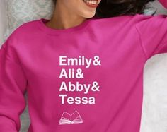 a woman laying on top of a bed wearing a pink shirt with the words family and albby & tessa printed on it