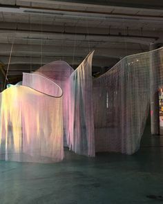 an art installation with sheer curtains hanging from it's sides in a large room