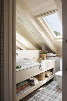 an attic bathroom with skylights and storage space for towels, toiletries and other items