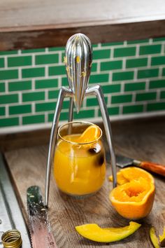 an orange juice is being squeezed into a glass with a fruit peeler on the side