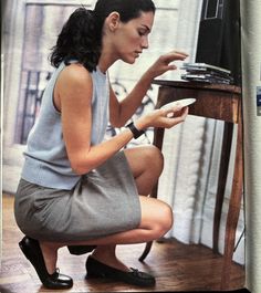 a woman sitting on the floor looking at her cell phone in front of a television