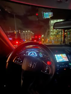 the interior of a car at night with red and green lights in the city street