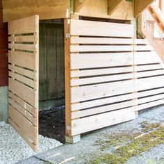 an outhouse with wood slats on the side and gravel in front of it