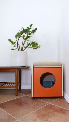 an orange box sitting on the floor next to a potted plant