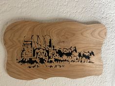 a wooden plaque with an image of a horse drawn carriage on it's side