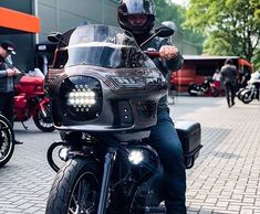 a man riding on the back of a motorcycle down a street next to other motorcycles