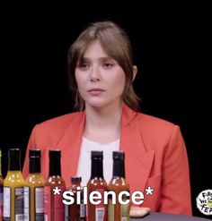 a woman sitting at a table with bottles of condiments in front of her