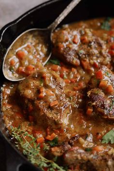 meatballs and carrots are in a skillet with a spoon