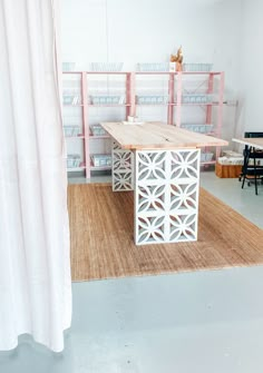 a white table sitting on top of a rug next to a wooden shelf filled with shelves