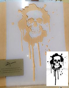 a skull is drawn on a piece of plywood paper with ink splatters