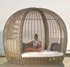 a woman sitting on top of a white bed next to the ocean