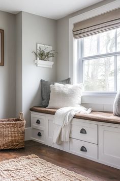 a window seat with pillows and blankets on it in front of a basket next to a window