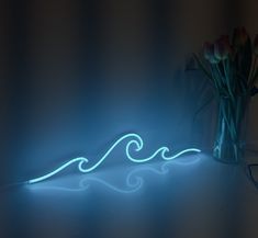 a vase filled with flowers sitting on top of a table next to a neon light