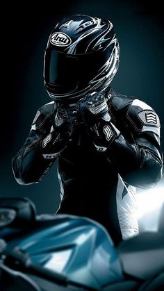 a man wearing a motorcycle helmet and holding his hands to his face while standing next to a motorbike