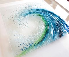 a painting with blue, green and white paint on it in the shape of a wave