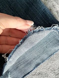 someone holding their hand on the side of a pair of jeans that have been ripped