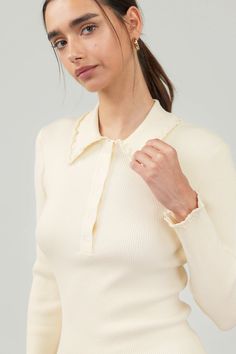 Introducing our Ivory Long Sleeve Top, a modern twist on a classic polo sweater. This soft and cozy knit features a tidy collar with playful ruffle detailing. Complete with a button placket and long sleeves, it's the perfect combination of sophistication and comfort. polo collar ruffle trim button placket long sleeves ribbed true to size model is wearing a small - Model Stats: 72% viscose 28% polyester hand wash cold White Elegant Collared Polo Sweater, Spring Collared Fine Knit Polo Sweater, Spring Fine Knit Collared Polo Sweater, Chic Long Sleeve Polo Sweater With Ribbed Collar, Elegant Beige Collared Polo Sweater, Elegant Cream Polo Sweater For Fall, Chic Collared Sweater With Seamless Collar, Spring Collared Fine Knit Sweater, Cream Long Sleeve Polo Sweater With Ribbed Cuffs