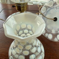 two glass vases sitting on top of a wooden table next to a lamp shade