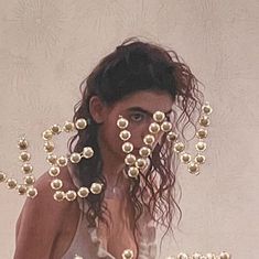 a woman with her hair blowing in the wind and beads hanging from her face behind her head