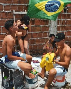 some people are sitting on the side of a building and one person is holding a yellow shirt